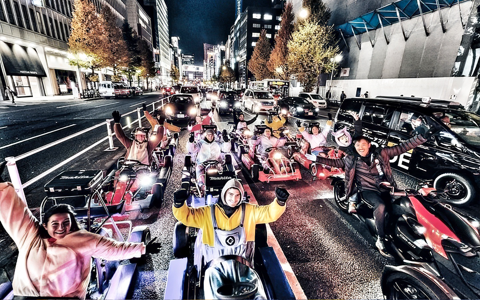 Group in costumes driving go-karts on a city street at night.