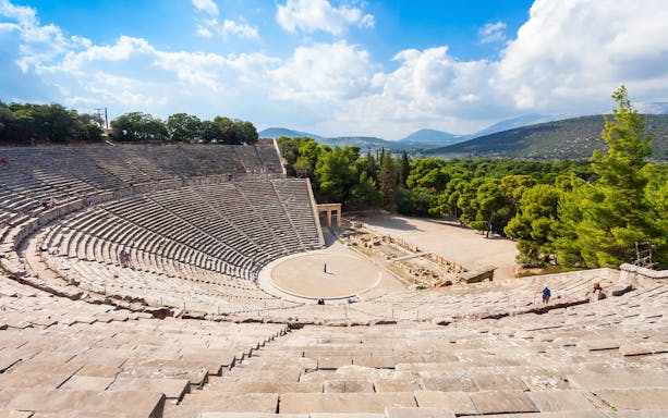 Epidaurus Ancient Theatre in Greece with stone seating and scenic landscape.