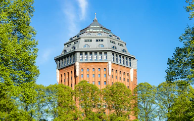 Sternschanze water tower surrounded by trees on a sunny day.