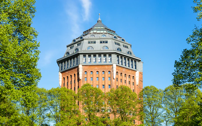 Sternschanze water tower surrounded by trees on a sunny day.