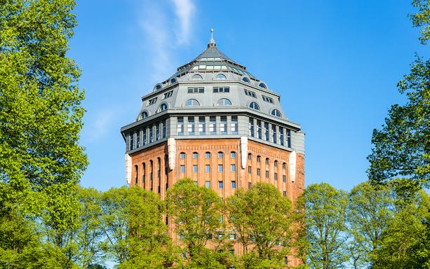 Sternschanze water tower surrounded by trees on a sunny day.