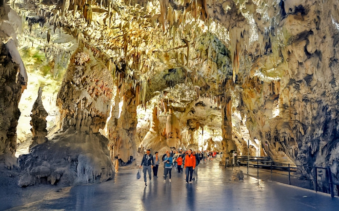 Visitors exploring stalactites and stalagmites inside Postojna Cave, Slovenia.