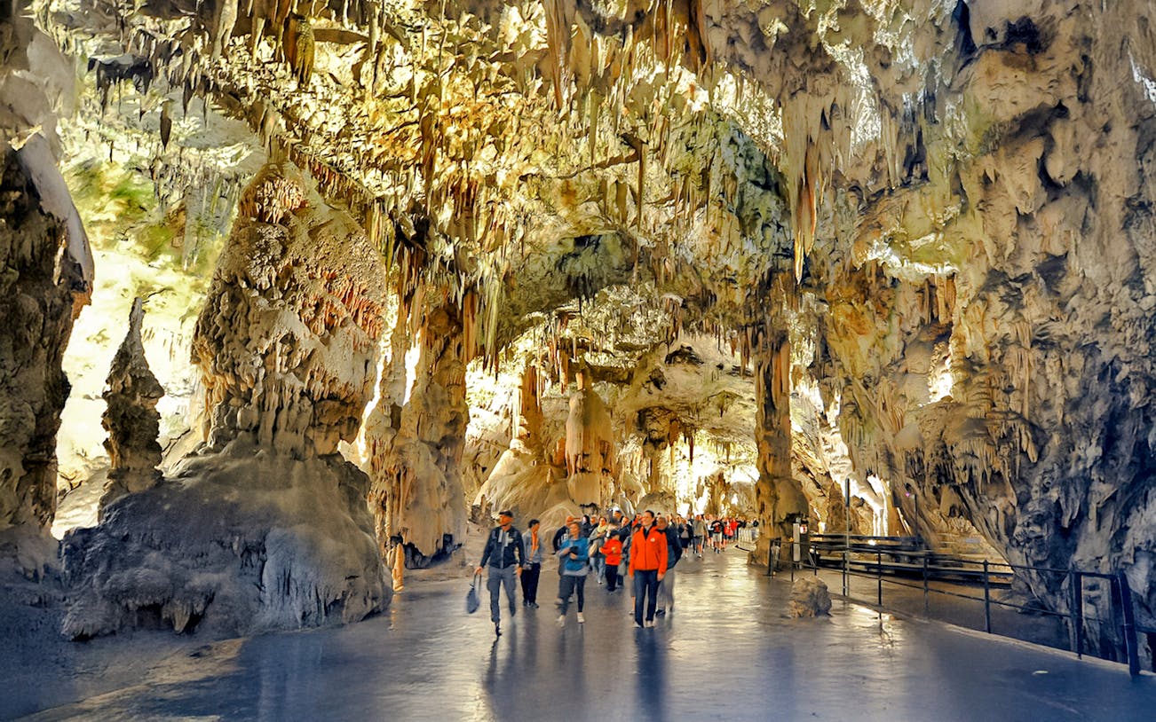 Visitors exploring stalactites and stalagmites inside Postojna Cave, Slovenia.