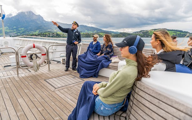 Captain guiding passengers on the panorama-yacht Saphir during a 1-hour scenic cruise with mountain views.