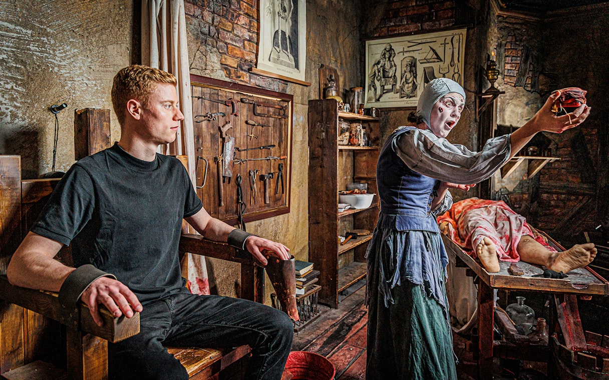 Man in a torture chamber with medieval tools at London Dungeon.
