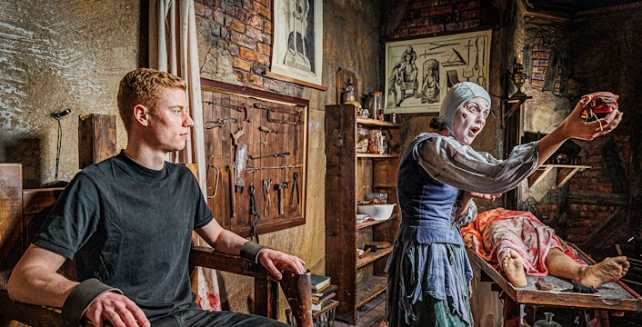 Man in a torture chamber with medieval tools at London Dungeon.