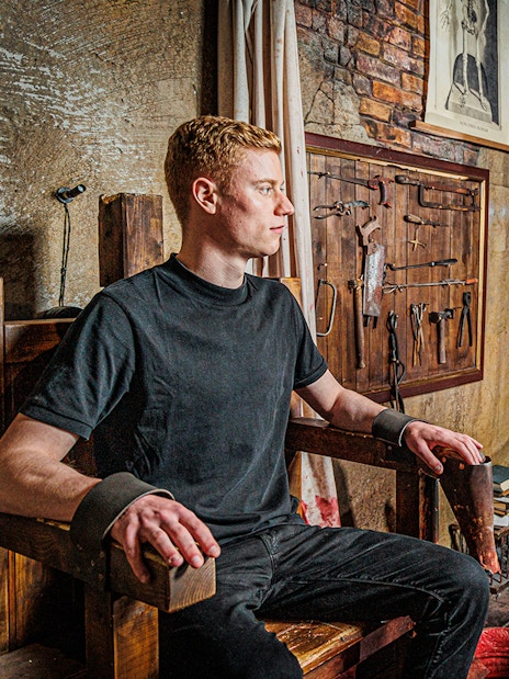 Man in a torture chamber with medieval tools at London Dungeon.