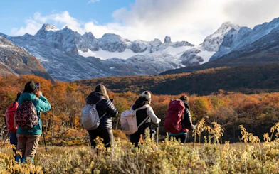 Hikers trekking towards Esmeralda Lake with snow-capped mountains in the background.