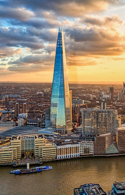The Shard skyscraper in London at sunset with cityscape and river views.