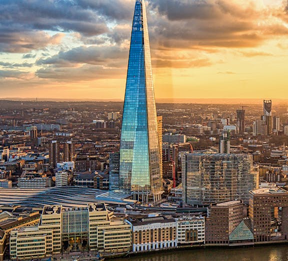 The Shard skyscraper in London at sunset with cityscape and river views.