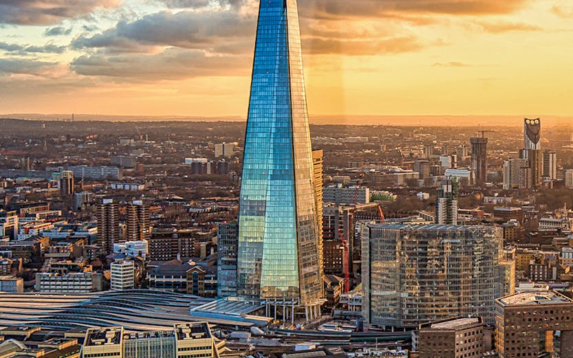 The Shard skyscraper in London at sunset with cityscape and river views.