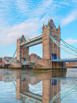 Tower Bridge spanning the Thames River in London, reflecting in the water.