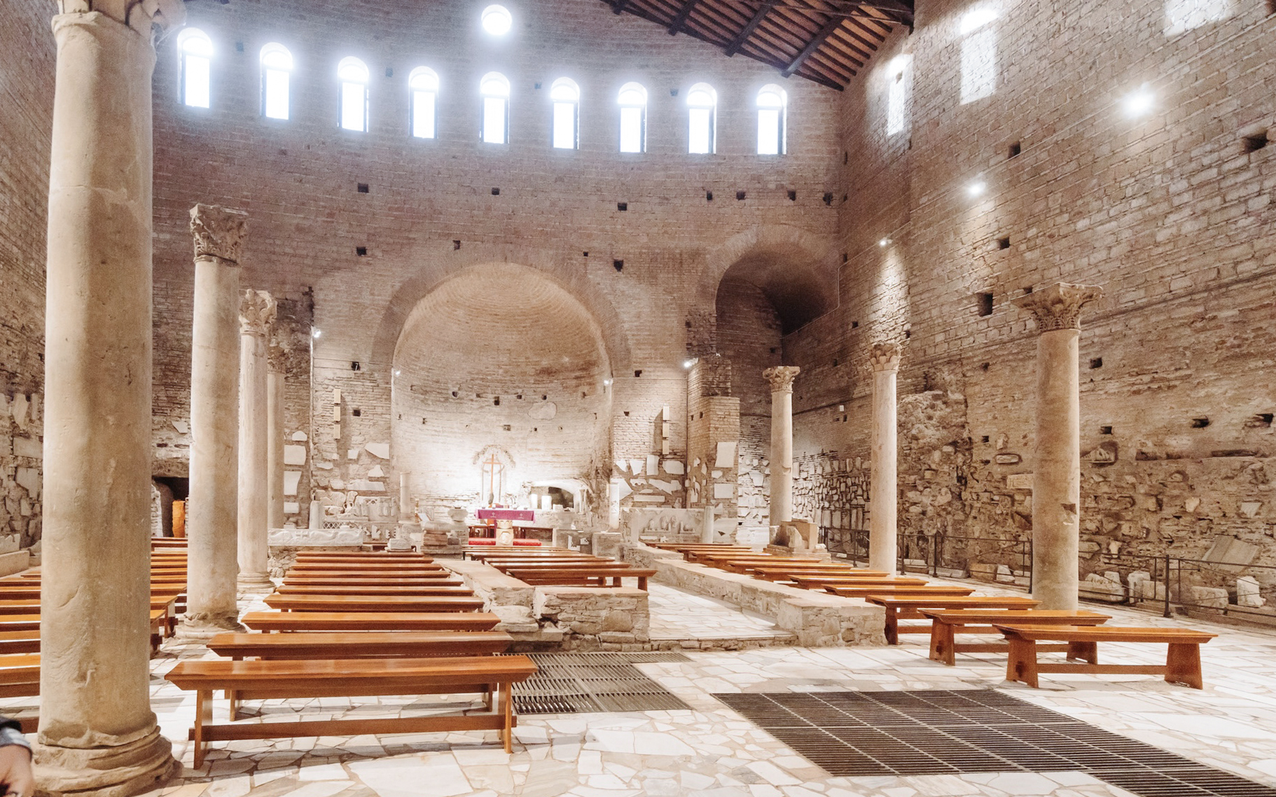 Interior of ancient Roman catacombs with stone columns and benches, part of the Underground Rome Catacombs Tour.