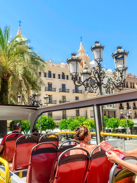Tourist on Cordoba sightseeing bus viewing historic architecture.