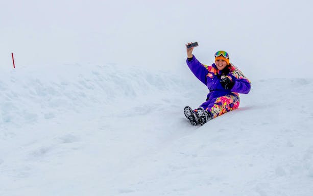 Tourist sliding on snow at Valle Nevado, Chile, capturing a selfie.