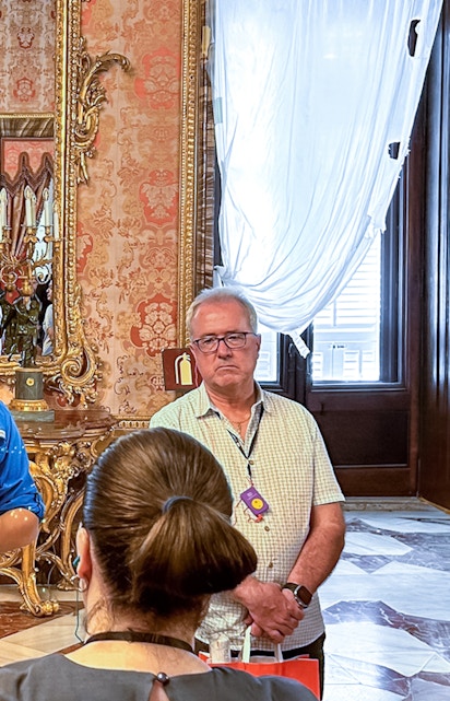 Guide explaining history to tourists inside Royal Palace of Madrid.