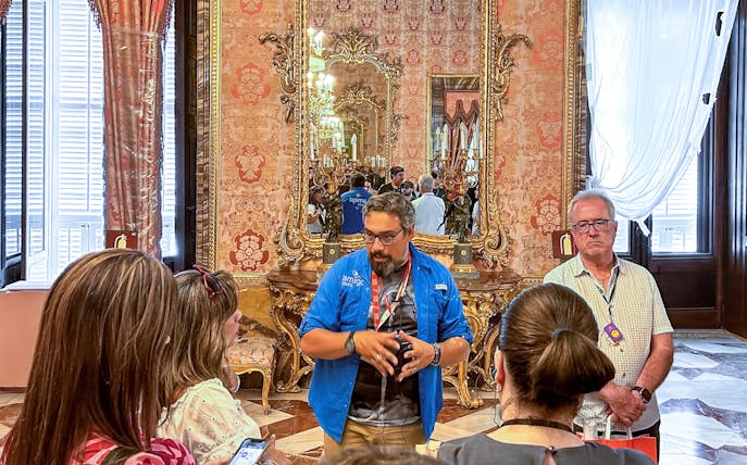 Guide explaining history to tourists inside Royal Palace of Madrid.