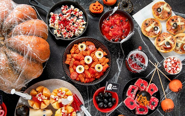 Halloween-themed food spread with pumpkin, pasta, and spooky treats for Energylandia Fast Track Entry offer.