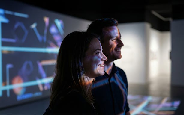 Couple enjoying digital art projections at an exhibition.