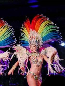 Performer in colorful feathered costume at Oh!César Cabaret Caribbean Nights Show.
