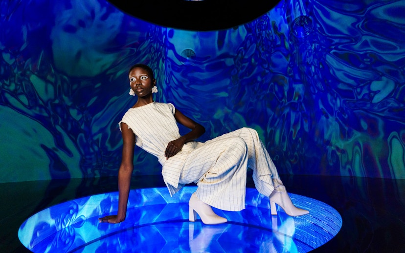 Person posing in a futuristic blue-lit room at AYA Universe.