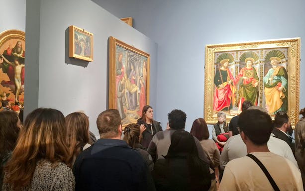 Visitors viewing Renaissance paintings at Florence's Accademia Gallery.