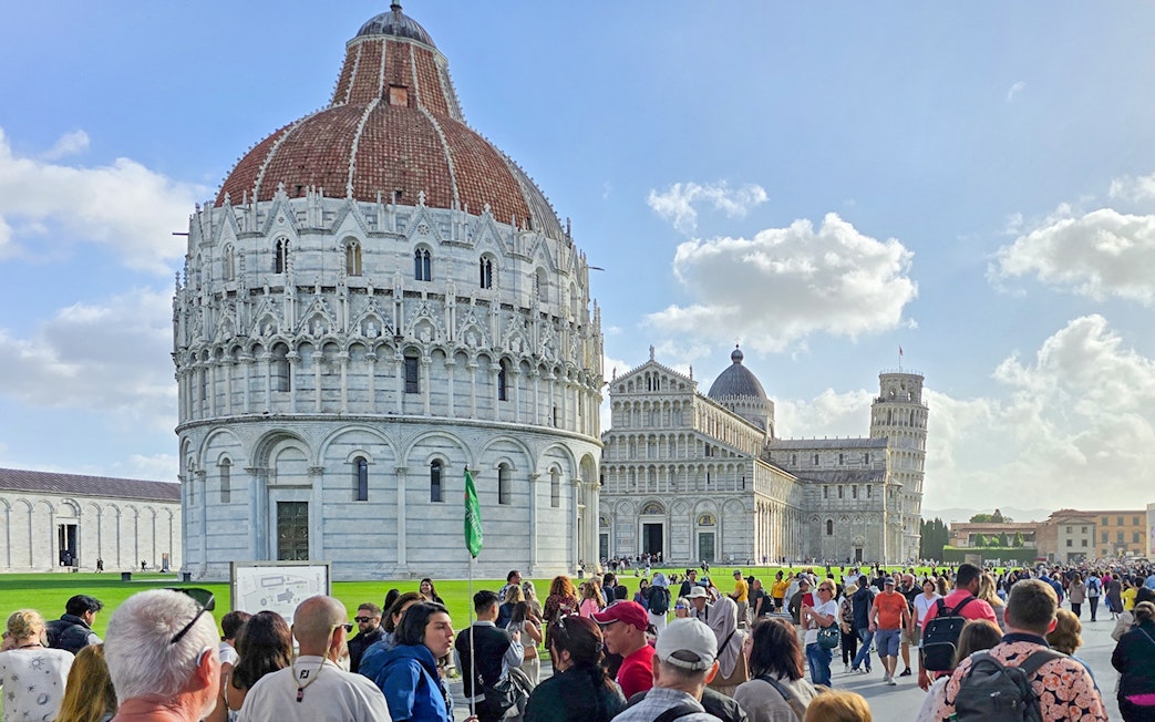 Visitors walking past the Pisa Baptistery towards the Cathedral in Italy.