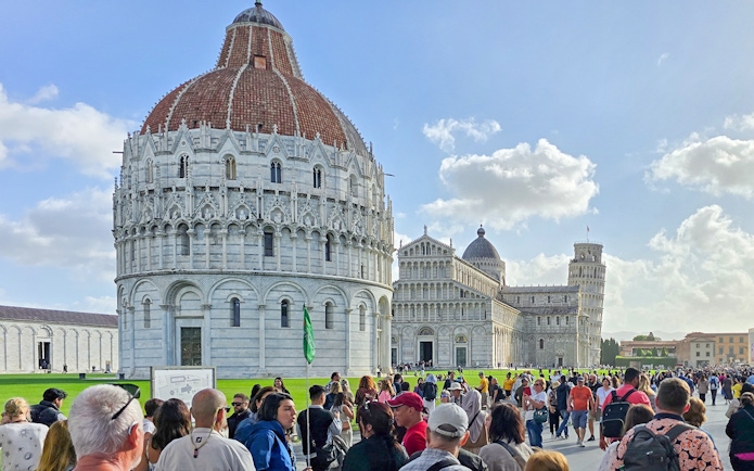 Visitors walking past the Pisa Baptistery towards the Cathedral in Italy.