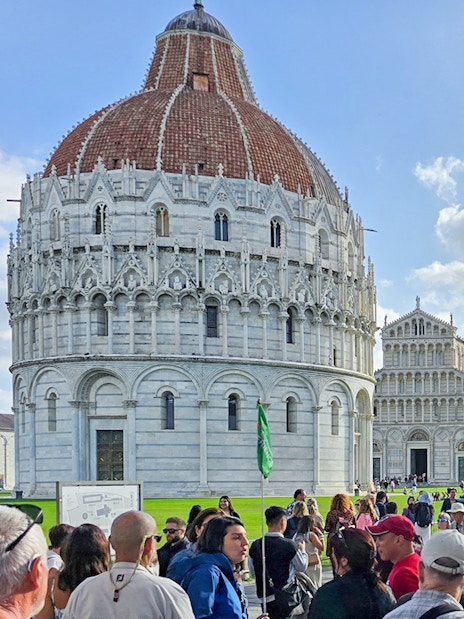 Visitors walking past the Pisa Baptistery towards the Cathedral in Italy.