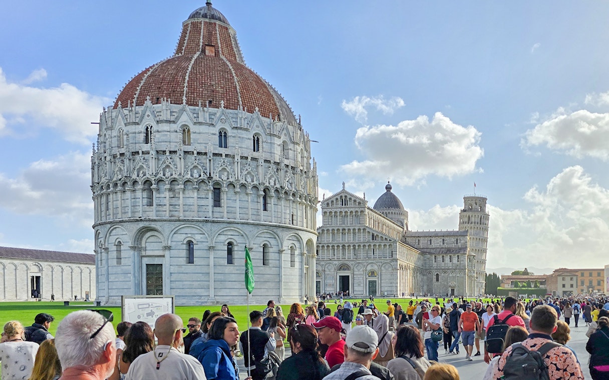 Visitors walking past the Pisa Baptistery towards the Cathedral in Italy.