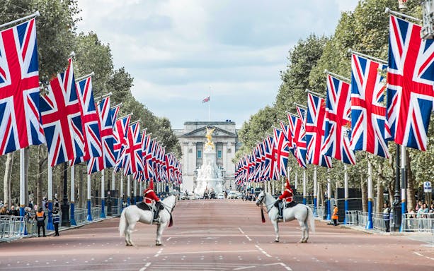 Buckingham Palace with Union Jacks and guards on horseback, London.