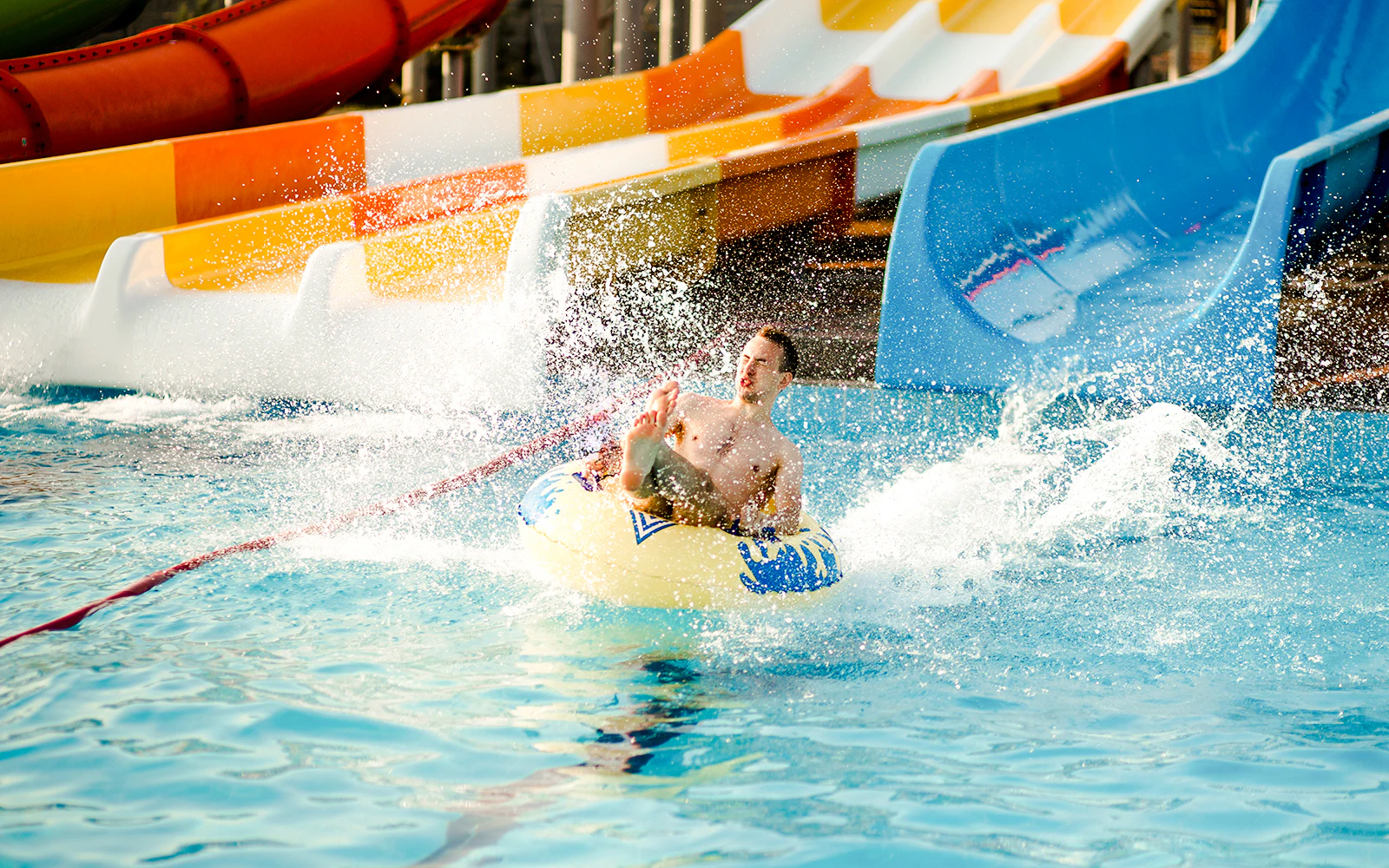 Person enjoying a water slide at a water park, splashing into the pool.