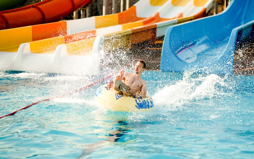 Person enjoying a water slide at a water park, splashing into the pool.