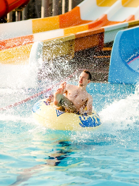 Person enjoying a water slide at a water park, splashing into the pool.
