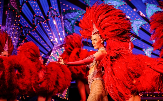 Moulin Rouge cabaret show in Paris with iconic red windmill and vibrant lights.