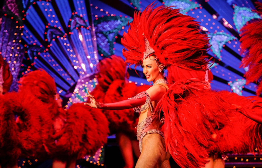 Moulin Rouge cabaret show in Paris with iconic red windmill and vibrant lights.