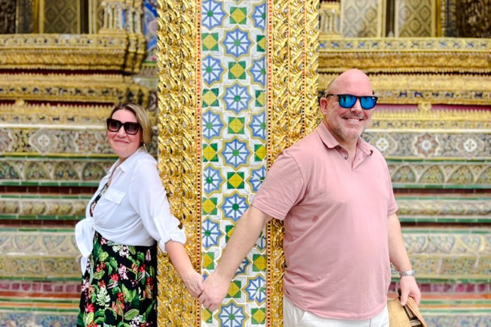 Visitors holding hands at ornate pillar, Grand Palace tour, Bangkok.