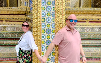Visitors holding hands at ornate pillar, Grand Palace tour, Bangkok.