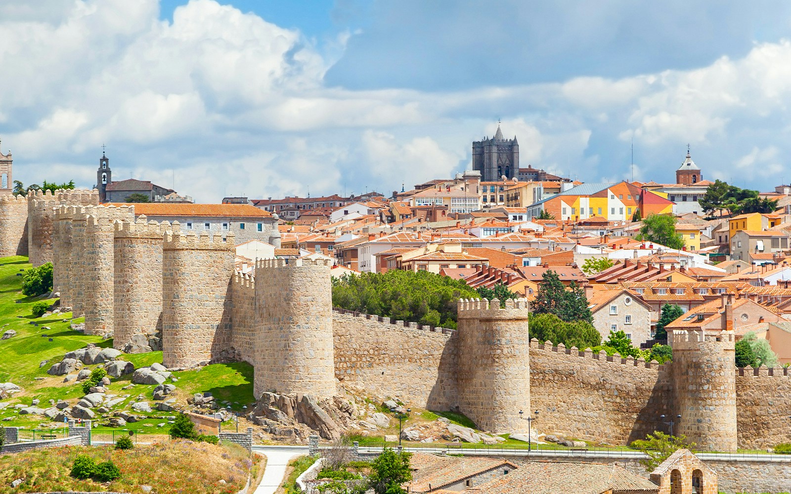 Medieval walls surrounding the historical city of Avila, Spain, with ancient stone towers and battlements.