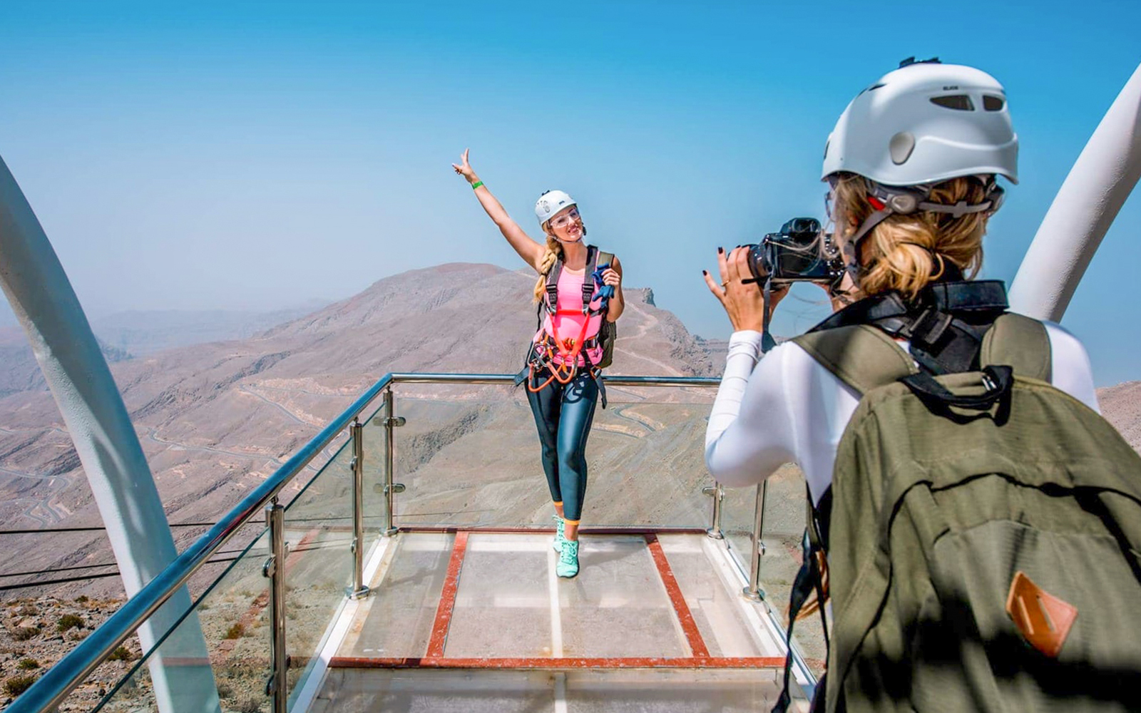 Person posing on Jebel Jais viewing platform, UAE, with photographer capturing the moment.