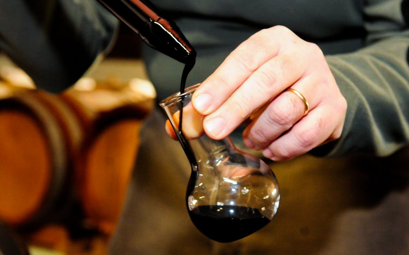 Pouring vinegar into a glass during a guided cellar tour with tastings.