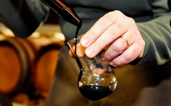 Pouring vinegar into a glass during a guided cellar tour with tastings.