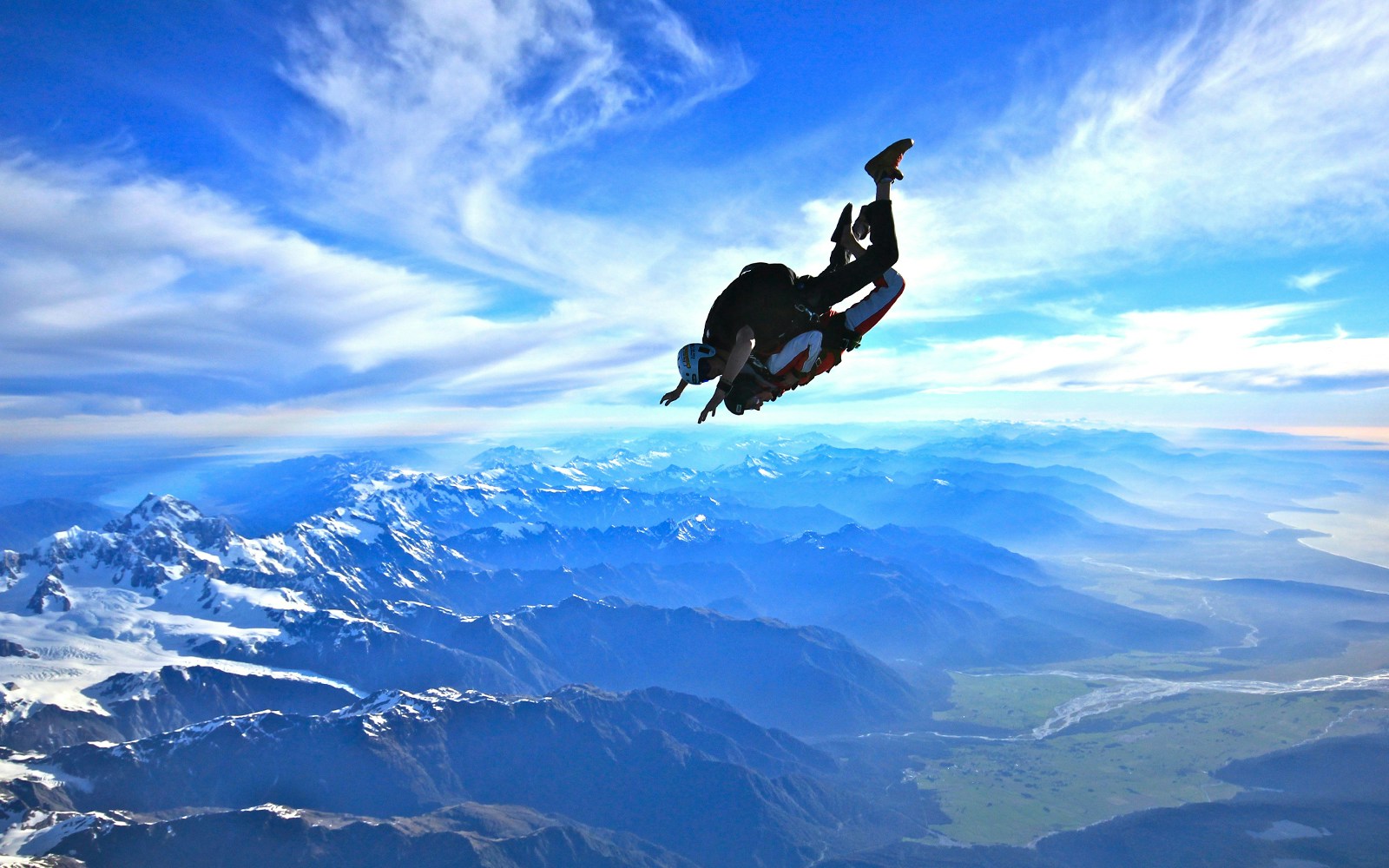 Skydiver over Franz Josef Glacier, New Zealand, with mountain views.