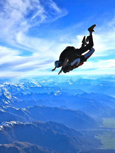 Skydiver over Franz Josef Glacier, New Zealand, with mountain views.