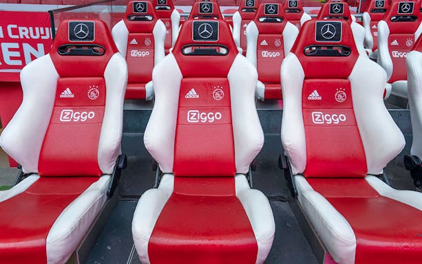 Red and white stadium seats with sponsor logos at Johan Cruijff Arena, Amsterdam.