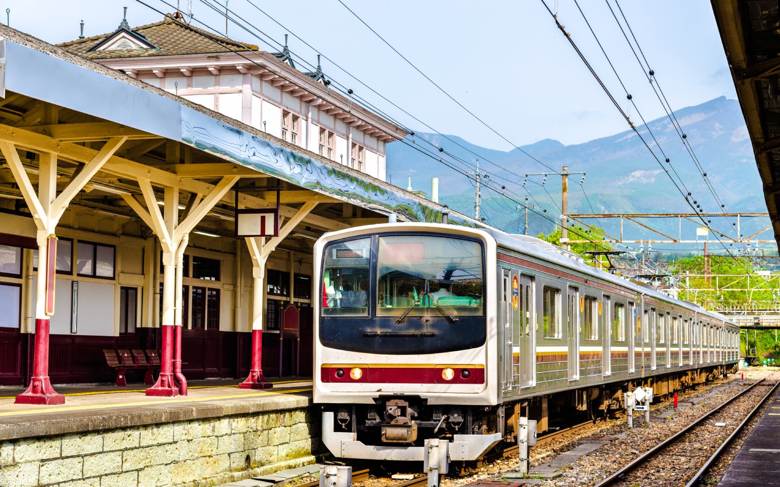 Local train at Nikko railway station, Japan with mountain backdrop.