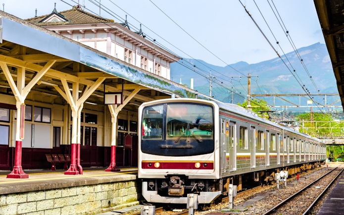 Local train at Nikko railway station, Japan with mountain backdrop.