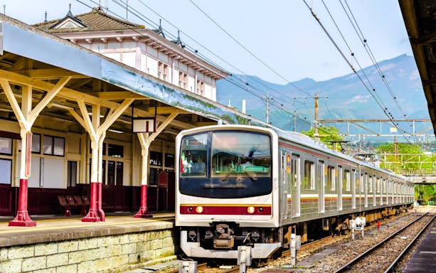 Local train at Nikko railway station, Japan with mountain backdrop.
