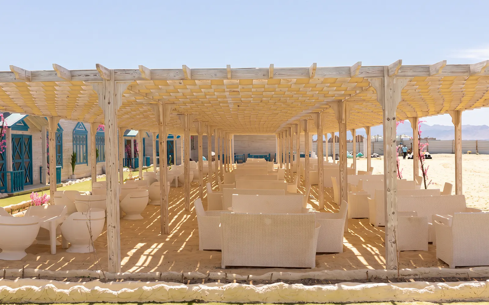 Outdoor seating area with wicker chairs under a wooden pergola on Bianca Island, Hurghada.
