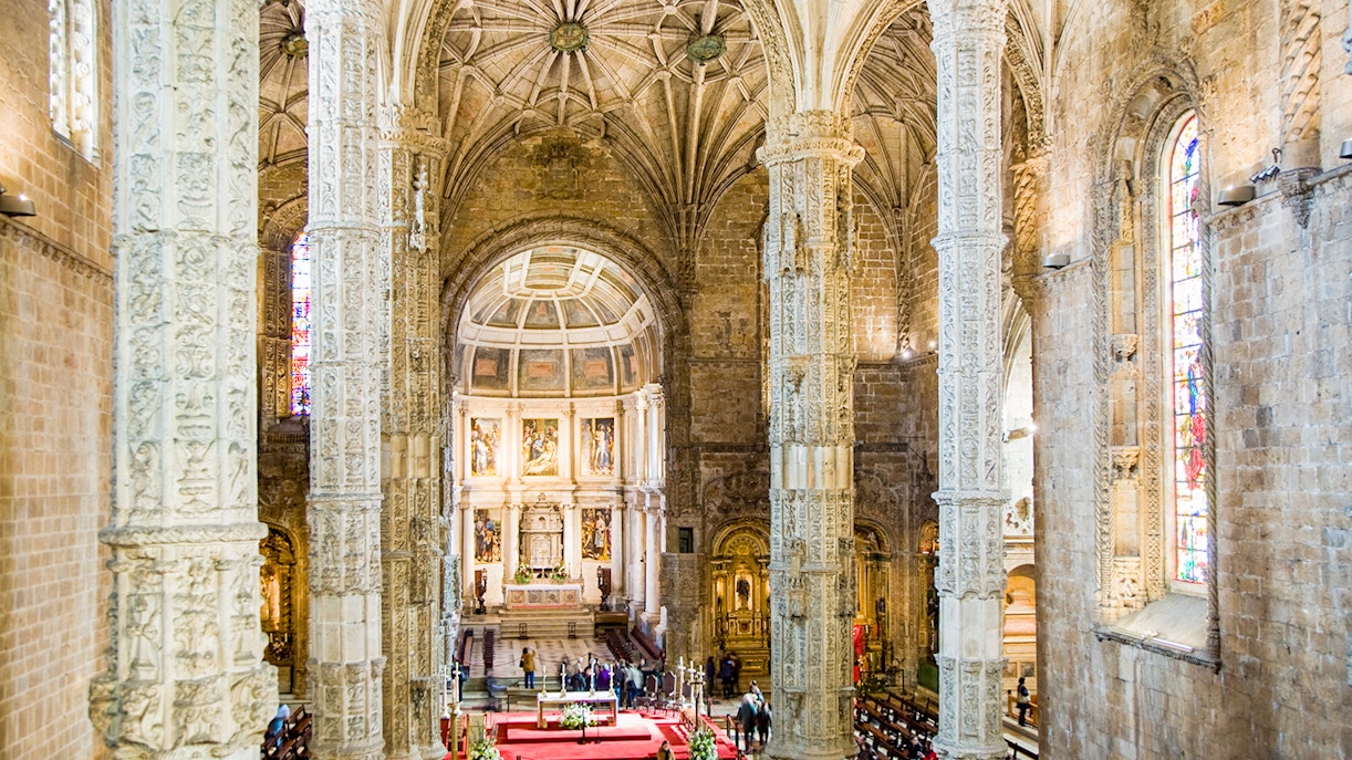 Jeronimos Monastery interior with ornate columns and altar in Lisbon.